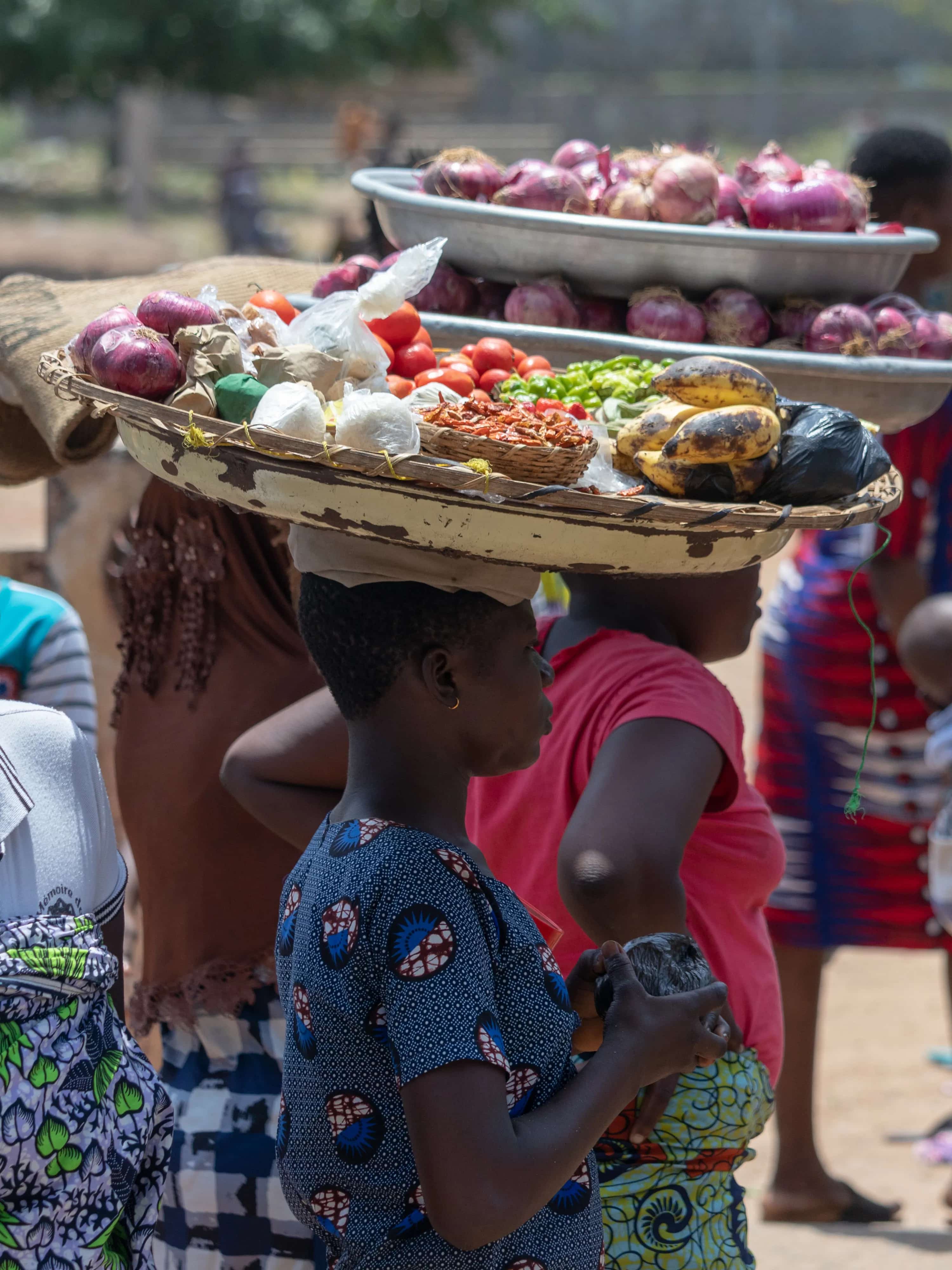Des femmes portent sur la tête des plateaux de légumes